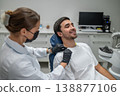 Female dentist putting bib on male patient 138877106