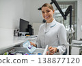 Female dentist taking sterile tool from drawer 138877120