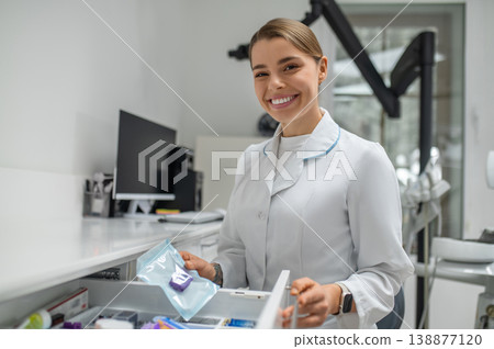 Female dentist taking sterile tool from drawer 138877120