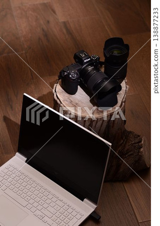Laptop rests beside camera gear on rustic wood stump Laptop rests beside camera gear on rustic wood stump 138877233