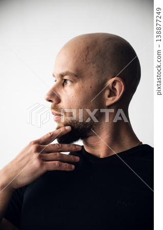 Man thinking with hand on chin in a simple background during daytime Man thinking with hand on chin in a simple background during daytime 138877249