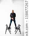 Man stands on two chairs in a studio with white background during a creative session 138877267