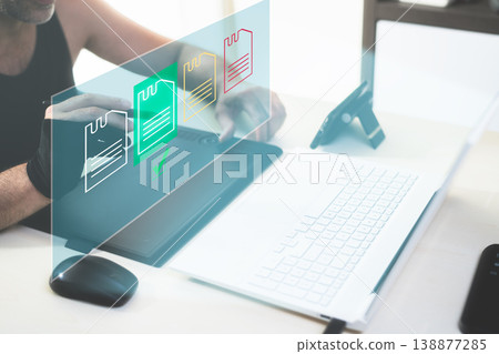 Man working from home on laptop managing data files on a virtual screen with a digital pen Man working from home on laptop managing data files on a virtual screen with a digital pen 138877285