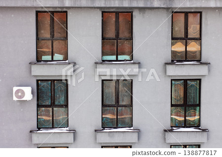 Charming winter evening with softly lit windows revealing inviting domestic tranquility 138877817