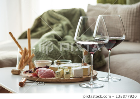 Cozy living room with two glasses of red wine and cheese on table Cozy living room with two glasses of red wine and cheese on table 138877920