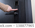 A woman opens a modern smart door lock with a digital keypad using a code. 138877965