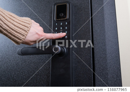 A woman opens a modern smart door lock with a digital keypad using a code. 138877965