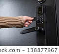 A woman opens a modern smart door lock using a contactless key. 138877967