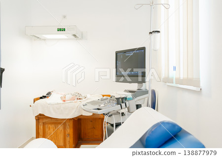 Baby prepared for ultrasound examination in hospital room. Concept of early diagnosis, safety, healthcare services and newborn monitoring Baby prepared for ultrasound examination in hospital room. Concept of early diagnosis, safety, healthcare services and newborn monitoring 138877979