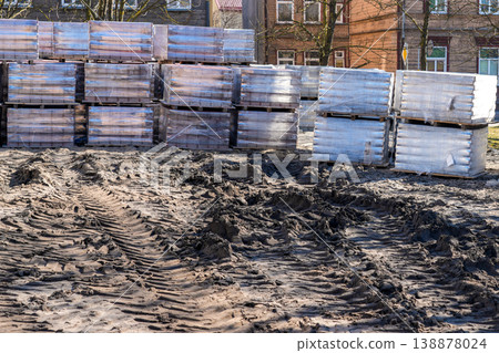 Square before reconstruction with stacked paving stone pallets and muddy tire tracks in urban area Square before reconstruction with stacked paving stone pallets and muddy tire tracks in urban area 138878024