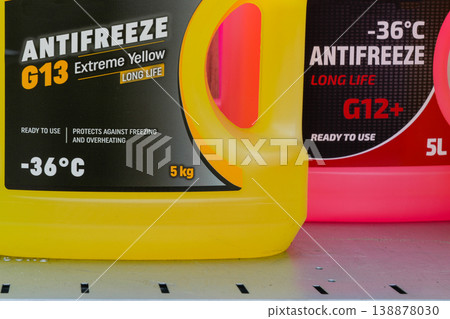 Colorful antifreeze containers G13 and G12 on shelf showing labels and automotive coolant specs 138878030
