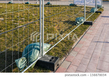 Temporary construction fence panels secured with sandbags along roadside work zone safety barrier 138878034