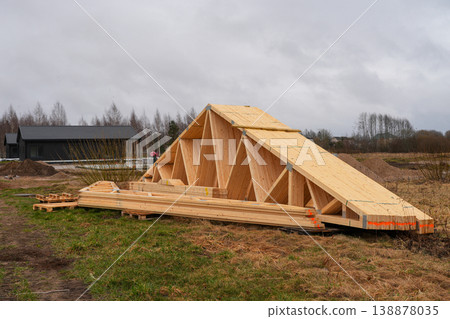 Prefabricated timber roof trusses stacked on pallets at rural construction site ready for assembly Prefabricated timber roof trusses stacked on pallets at rural construction site ready for assembly 138878035