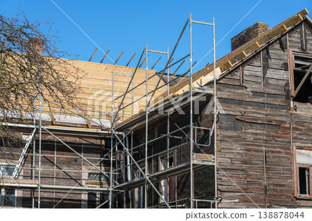 Close view of old wooden house renovation with scaffolding and new timber roof structure 138878044