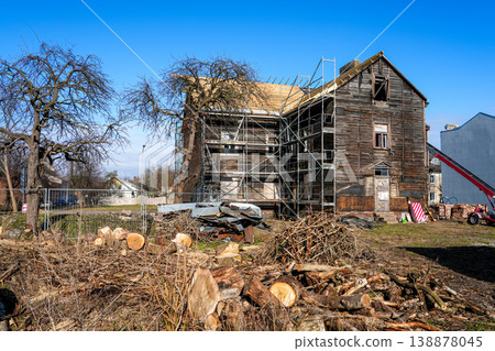 Old wooden house renovation with scaffolding, debris and tree cutting in residential yard Old wooden house renovation with scaffolding, debris and tree cutting in residential yard 138878045
