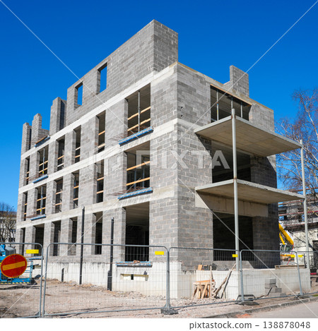 Modern concrete block apartment building under construction with balconies and clear blue sky Modern concrete block apartment building under construction with balconies and clear blue sky 138878048
