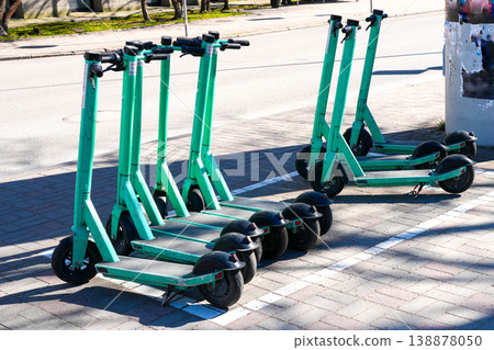 Row of shared electric scooters parked on city sidewalk ready for urban transport rental use Row of shared electric scooters parked on city sidewalk ready for urban transport rental use 138878050