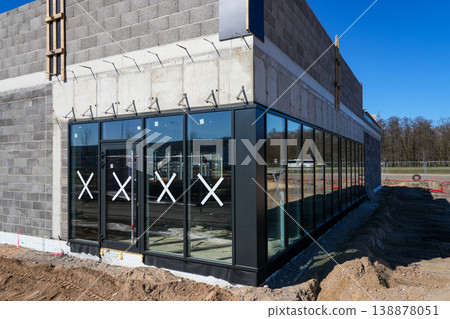 Modern commercial building facade with glass windows under construction and unfinished exterior Modern commercial building facade with glass windows under construction and unfinished exterior 138878051