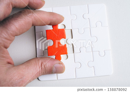 Person hand holds a red jigsaw puzzle piece. 138878092