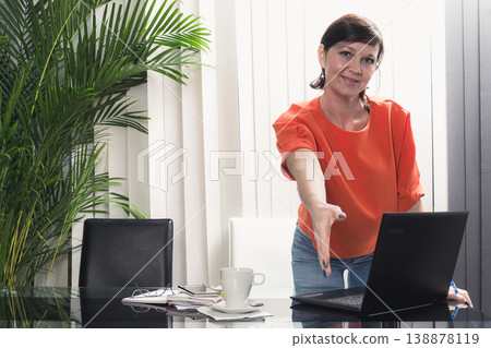 Smiling and happy business woman working with her mobile phone and laptop in the office. 138878119