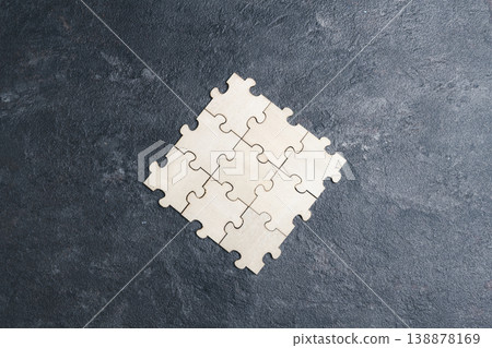 Unfinished wooden jigsaw puzzle on a black background. Unfinished wooden jigsaw puzzle on a black background. 138878169