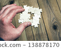 A hand is holding a puzzle piece that is missing 138878170