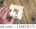 A hand is holding a puzzle piece that is missing 138878173