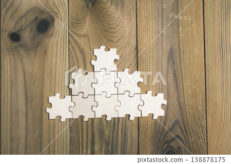 Puzzle pieces arranged in a pyramid shape on a wooden table. 138878175