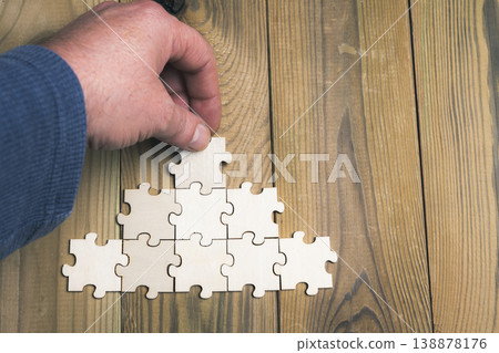 A hand is holding a puzzle piece that is part of a larger puzzle A hand is holding a puzzle piece that is part of a larger puzzle 138878176