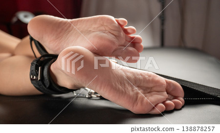 Women's legs in leather shackles. BDSM fetish. Women's legs in leather shackles. BDSM fetish. 138878257