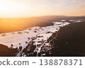 The scene shows Jizerka mountain village covered in snow during winter. A drone captures the village layout, the trees, and the snow-covered land under a sunset sky. 138878371