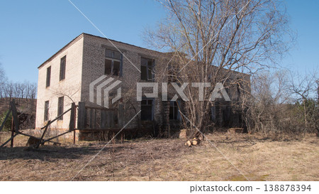 Abandoned Concrete Two Story Dormitory Near Trees, Boarded Windows, Stacked Logs, Ragged Entrance, Open Field, Abandoned Concrete Two Story Dormitory Near Trees, Boarded Windows, Stacked Logs, Ragged Entrance, Open Field, 138878394