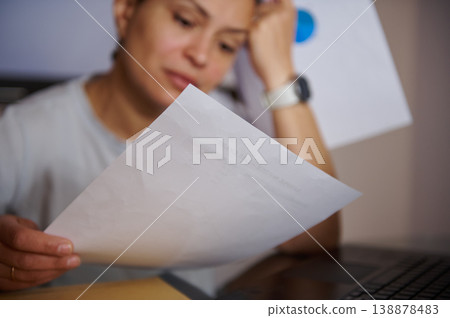 Stressed Woman Reviewing Bills and Paperwork at Home Office Desk With Laptop Stressed Woman Reviewing Bills and Paperwork at Home Office Desk With Laptop 138878483