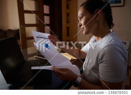 Woman Reviewing Financial Documents at Home Office With Laptop for Remote Work and Budget Planning 138878501