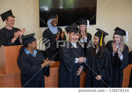 Young multinational people in graduation gowns congratulate each other on graduation from university. Young multinational people in graduation gowns congratulate each other on graduation from university. 138878524