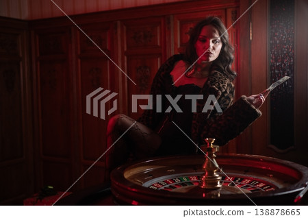 A beautiful brunette in a black dress at the casino roulette wheel. A beautiful brunette in a black dress at the casino roulette wheel. 138878665