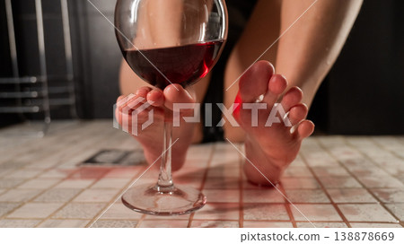 Foot fetish. A woman pours wine from a glass onto her feet in the shower. 138878669