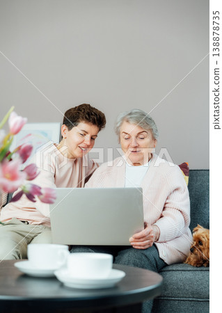 Adult woman explaining senior mother how to use laptop. Education for aged. Retired lady discovering technology for reading news, chatting with family, watching video, online consulting with doctor. Adult woman explaining senior mother how to use laptop. Education for aged. Retired lady discovering technology for reading news, chatting with family, watching video, online consulting with doctor. 138878735