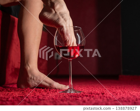 Foot fetish. A woman dips her toes in a glass of red wine. Foot fetish. A woman dips her toes in a glass of red wine. 138878927