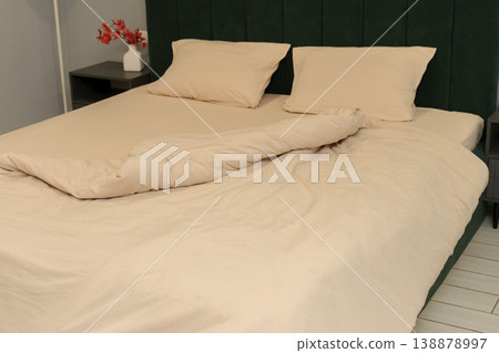 Cozy bedroom with unmade bed and decorative flowers on nightstand Cozy bedroom with unmade bed and decorative flowers on nightstand 138878997