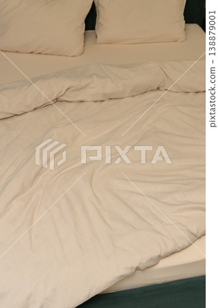 Soft white bedding with wrinkled duvet and two pillows on bed 138879001