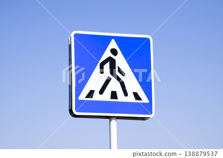 A pedestrian crossing sign. Sign on a blue sky background. A pedestrian crossing sign. Sign on a blue sky background. 138879537