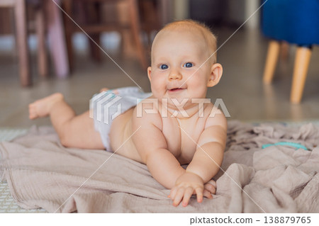 Baby lying on play mat learning to crawl and get on all fours. Infant practicing motor skills and development at home. Early childhood growth, milestones and active learning concept 138879765