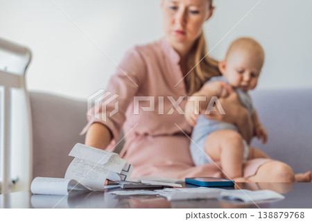 Mother sitting on sofa holding baby while calculating monthly expenses with receipts at home. Stressed mom managing budget and childcare. Financial stress, parenthood and real life concept Mother sitting on sofa holding baby while calculating monthly expenses with receipts at home. Stressed mom managing budget and childcare. Financial stress, parenthood and real life concept 138879768