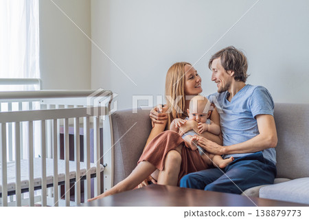 Mother and father sitting on sofa hugging their baby at home. Loving parents embracing newborn with tenderness and care. Family bonding, parenthood, warmth and emotional connection concept Mother and father sitting on sofa hugging their baby at home. Loving parents embracing newborn with tenderness and care. Family bonding, parenthood, warmth and emotional connection concept 138879773