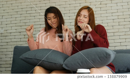 Two pretty best friends forever girlfriend talk, hug and laugh together sitting on sofa in cozy home relax. Happy friendship smile talking together positive emotion in living room joyful lifestyles 138879909