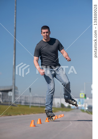 A Caucasian man rollerblades around the slalom course. 138880028