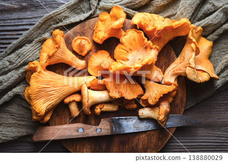 Chanterelle mushrooms piled on a wooden cutting board Chanterelle mushrooms piled on a wooden cutting board 138880029