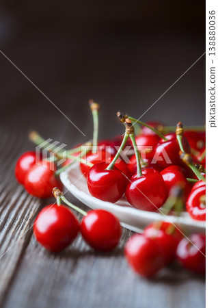 Close up of sweet cherries with green stems on rustic table Close up of sweet cherries with green stems on rustic table 138880036