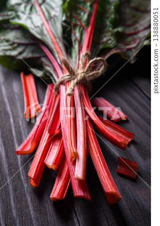 Fresh chard stalks tied with string on dark wooden surface 138880051